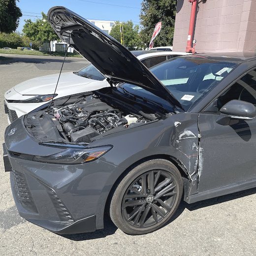 A grey Toyota Camry with side damage waiting for repair