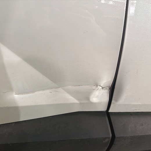 Close-up of a crease in a white door panel before repair