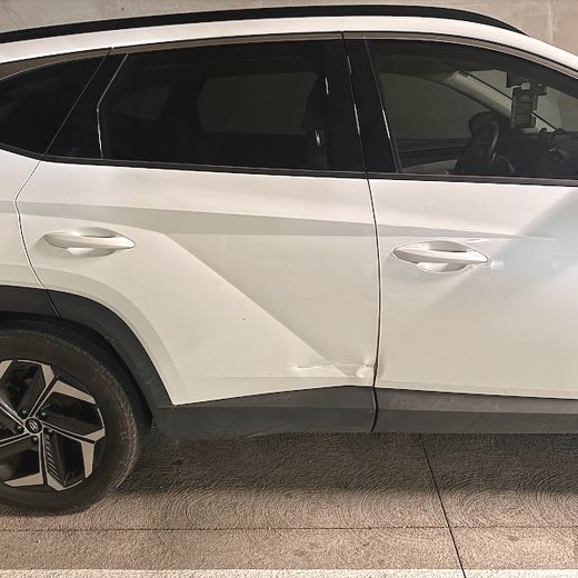 White Hyundai Tucson with dented driver-side doors