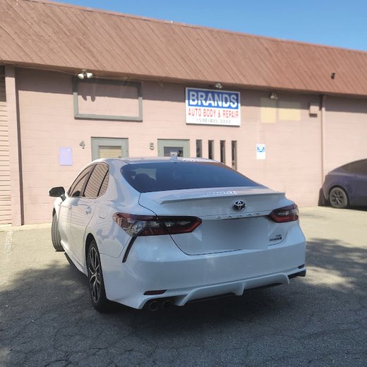 A white Toyota Camry finished and parked outside the shop