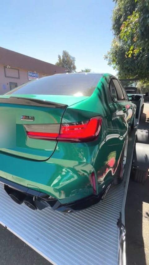 Green BMW M3 being unloaded from a flatbed at the shop